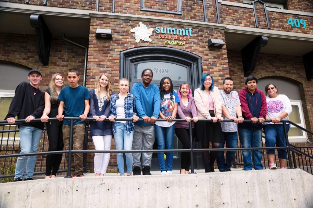 A group of diverse students taking a shot in front of the Summit Public School Olympus